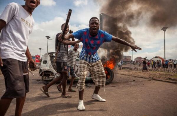 Des jeunes manifestent devant un véhicule en flammes à Kinshasa, le 19 
septembre 2016. ©AFP/Eduardo Soteras

