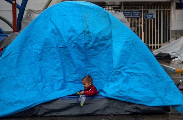 A Central American migrant boy, plays in a tent while camping near a closed temporary shelter a few meters from the US-Mexico border in Tijuana, Baja California state, Mexico, on December 5, 2018