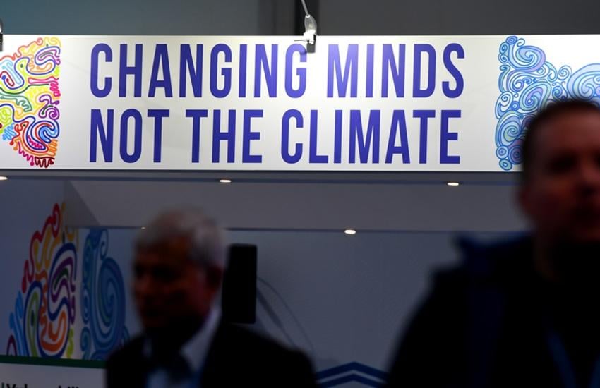Visitors stand in front of a banner reading "changing minds, not the climate" at a pavillion on November 8, 2017 during the COP23 United Nations Climate Change Conference in Bonn, Germany