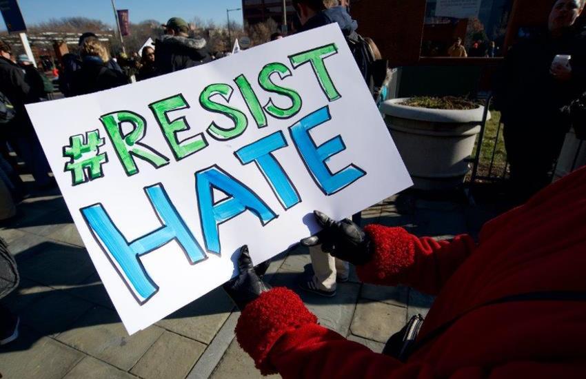 Protestor holding a sign saying Resist Hate