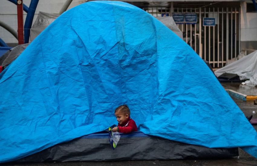 A Central American migrant boy, plays in a tent while camping near a closed temporary shelter a few meters from the US-Mexico border in Tijuana, Baja California state, Mexico, on December 5, 2018