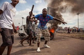Des jeunes manifestent devant un véhicule en flammes à Kinshasa, le 19 
septembre 2016. ©AFP/Eduardo Soteras

