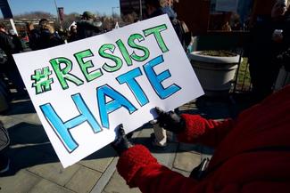 Protestor holding a sign saying Resist Hate