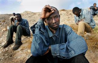Illegal immigrants rest on a beach after arriving on a makeshift boat in Fuerteventura, one of Spain's Canary Islands, October 10, 2004