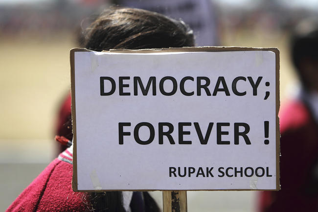 Child holding up sign saying Democracy forever